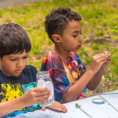 Two boys creating a potion at an outdoor summer camp.